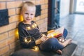 Christmas background. The boy is sitting near the fireplace with a book. Child with yellow lights. Waiting for the new year. Royalty Free Stock Photo