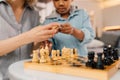 Boy sitting near of his parents and playing at chess with them Royalty Free Stock Photo