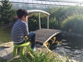 Boy sitting near a pond with a fishing rod.