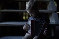 The boy is sitting on the old wooden stairs and playing the accordion. Royalty Free Stock Photo