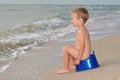 Boy sitting on a potty on the seashore Royalty Free Stock Photo