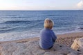 Boy sitting on rocks near sea shore waiting Royalty Free Stock Photo