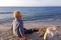 Boy sitting on rocks near sea shore waiting Royalty Free Stock Photo