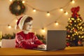 Boy sitting in a room with Christmas decor in front of a laptop with a surprised expression on face. Royalty Free Stock Photo
