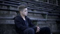 Boy sitting on stadium tribune, devastation and poverty around, city after war Royalty Free Stock Photo