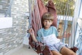 Boy is sitting, swinging in rattan swing chair during summer holidays , outdoors having fun. Royalty Free Stock Photo