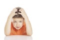 The boy is sitting at the table, holding his head with his hands. Close-up, free space for text. Isolated on a white background Royalty Free Stock Photo