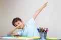Boy sitting at the table and shows dab gesture