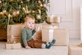 Boy sitting under Christmas tree with gift Royalty Free Stock Photo