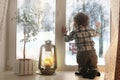 Boy sitting on a white window sill and looks out the window Royalty Free Stock Photo