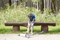 Boy sitting on the wooden bench in the park. Child fell while riding his scooter and hurt leg Royalty Free Stock Photo