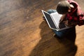 Boy sitting on wooden floor using laptop Royalty Free Stock Photo