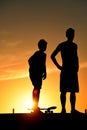 Boy with skateboard and friend on summer sunset Royalty Free Stock Photo