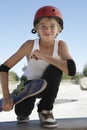 Boy With Skateboard Squatting In Skate Park