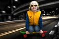 The boy skates on a skateboard through the night city.Extreme sports,fashion children. Royalty Free Stock Photo