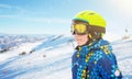 Boy with ski green helmet, yellow glasses and blue jacket at the ski center
