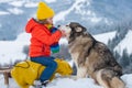 Boy sledding, enjoying sleigh ride. Child sitting on the sleigh with siberian husky dog. Children play with snow. Winter Royalty Free Stock Photo