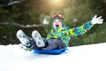 Boy sledding in a snowy forest. Outdoor winter fun for Christmas vacation. Royalty Free Stock Photo