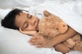 Boy sleeping on bed with teddy bear white pillow and sheets Royalty Free Stock Photo