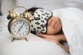 Boy sleeping on bed white piilow and sheets with alarm clork wearing sleep mask Royalty Free Stock Photo