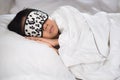 Boy sleeping on bed white pillow and sheets with sleep mask Royalty Free Stock Photo