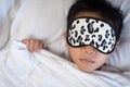 Boy sleeping on bed white pillow and sheets with sleep mask Royalty Free Stock Photo