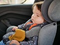 The boy is sleeping in a car seat. Driving safety for the child. 0-1 year old baby sleeping in a car seat