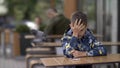 Boy sleeping sitting at a table in a cafe outdoors, doves in the background Royalty Free Stock Photo