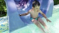 Boy slide on slider in water park on summer holiday. Happy boy sliding down the water slide.