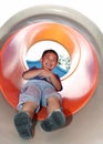 Boy sliding down on a cylindric slide