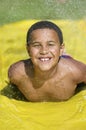 Boy (7-9) sliding on water slide front view portrait.