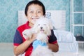 Boy smiling and carrying his cute dog in bedroom Royalty Free Stock Photo