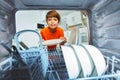 Boy smiling take plates from dishwashing machine