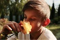 The boy sniffs a rose flower and enjoys the smell