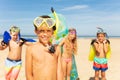 Boy in snorkeling mask stand with group of friends