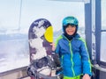 Boy with snowboard in the cabin of a chairlift holding board Royalty Free Stock Photo