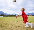 Boy, soccer ball and playing on green grass for sports, training or practice with clouds and blue sky. Young football Royalty Free Stock Photo