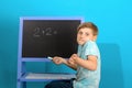 The boy solves the math equation 2 + 2 written on the blackboard. The child does not know the answer to simple examples