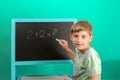 The boy solves the math equation 2 + 2 written on the blackboard. The child does not know the answer to simple examples Royalty Free Stock Photo