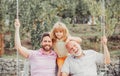 Boy son with father and grandfather swinging together in park outdoors. Three different generations ages grandfather Royalty Free Stock Photo