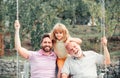 Boy son with father and grandfather swinging together in park outdoors. Three different generations ages grandfather Royalty Free Stock Photo