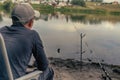 A boy with a spinning rod is fishing. Bank of a river or lake on a summer morning. Smartphone for social networking