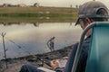 A boy with a spinning rod is fishing. Bank of a river or lake on a summer morning. Smartphone for social networking