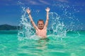 Boy splashing water in sea. Playful child 10 years old surrounded by colorful nature. Bright blue sky and shimmering sea. Royalty Free Stock Photo