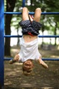 The boy on the sports ground caught his feet on the stairs and hangs upside down