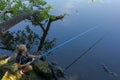 A boy squats on rocks and catches fish. Sport fishing on the river in summer Royalty Free Stock Photo