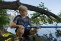 A boy squats on rocks and catches fish. Sport fishing on the river in summer Royalty Free Stock Photo