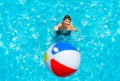 Little boy stand in pool and throw inflatable ball