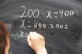 Boy standing back in front of school blackboard and writing. Schoolboy solves math example at the chalkkboard Royalty Free Stock Photo
