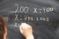 Boy standing back in front of school blackboard and writing. Schoolboy solves math example at the chalkkboard